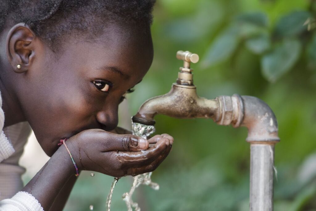 Bambina che beve acqua da rubinetto