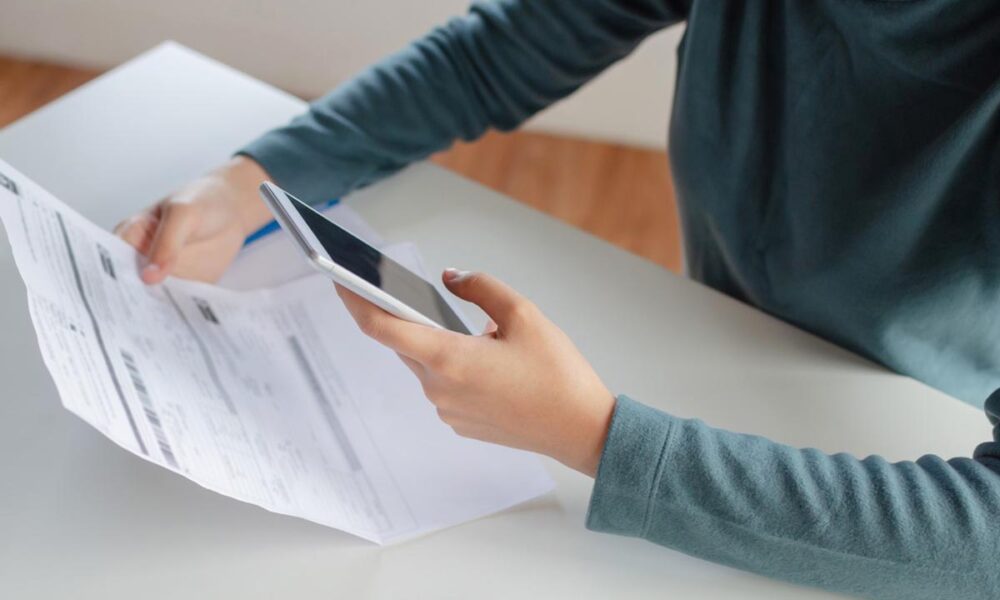 Lavoratore che tiene in mano la busta paga calcolando lo stipendio con lo smartphone