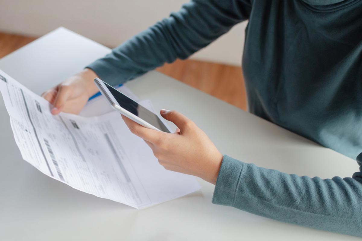 Lavoratore che tiene in mano la busta paga calcolando lo stipendio con lo smartphone