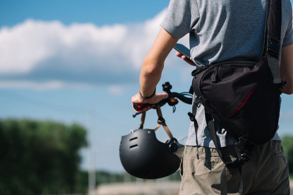 Ragazzo a bordo del suo monopattino con il casco appoggiato sul manubrio