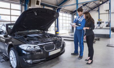 Meccanico che analizza la revisione con una cliente di fronte alla propria auto