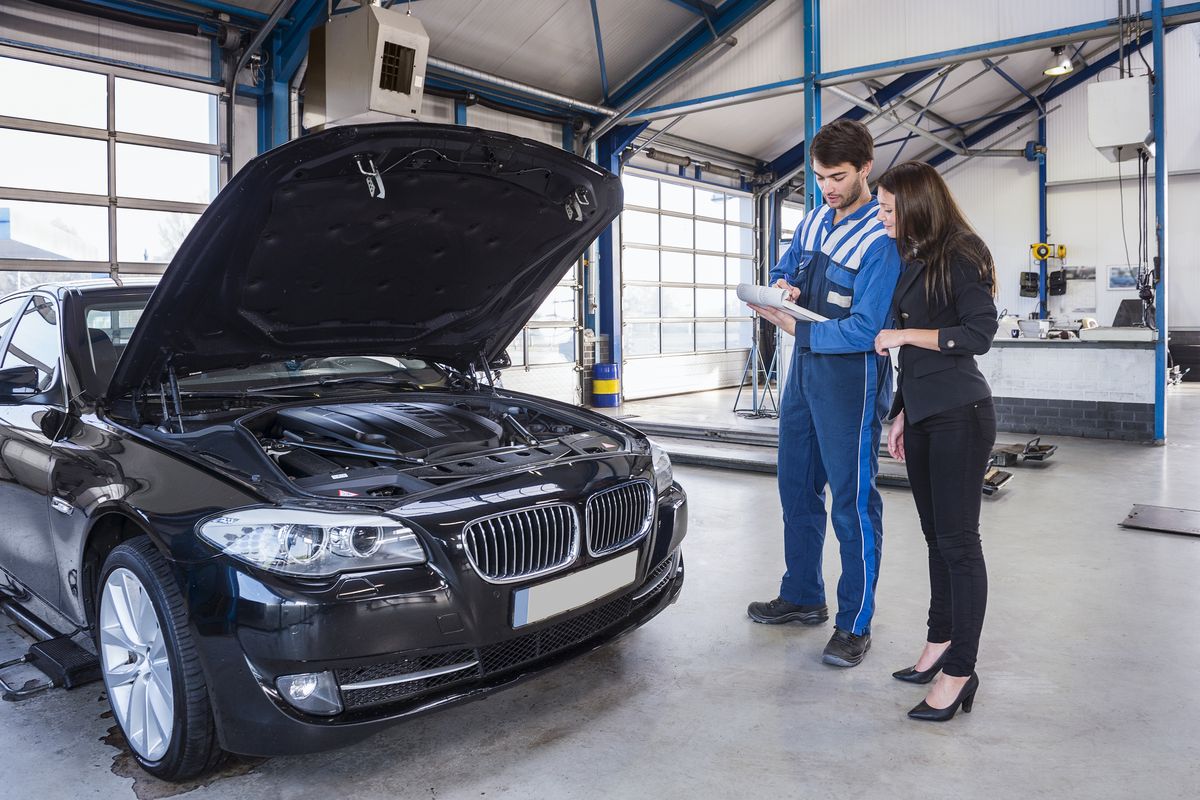 Meccanico che analizza la revisione con una cliente di fronte alla propria auto