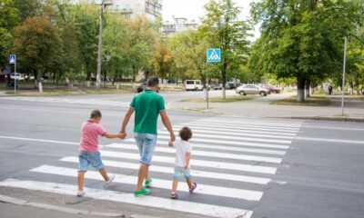 Padre che attraversa sulle strisce pedonali con i figli