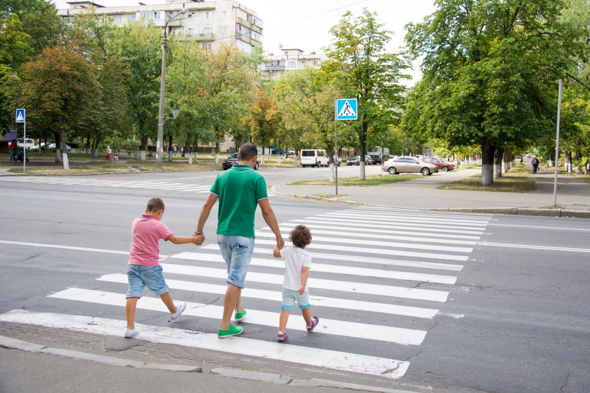 Padre che attraversa sulle strisce pedonali con i figli