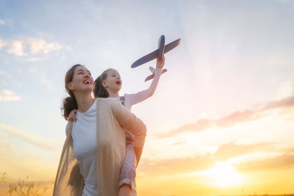 Mamma che gioca con la figlia che tiene in mano un modellino di un aereo