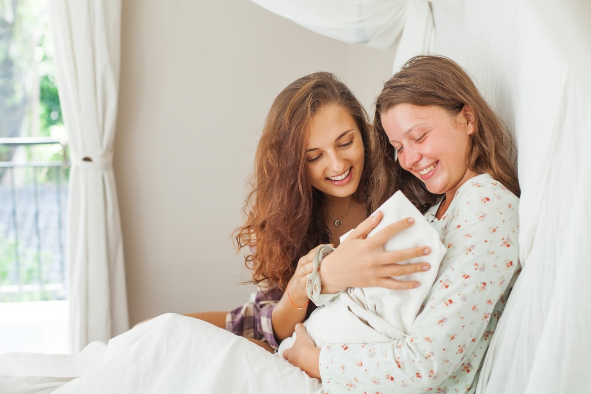 Neo mamma tiene in braccio il figlio con a fianco sorella felice