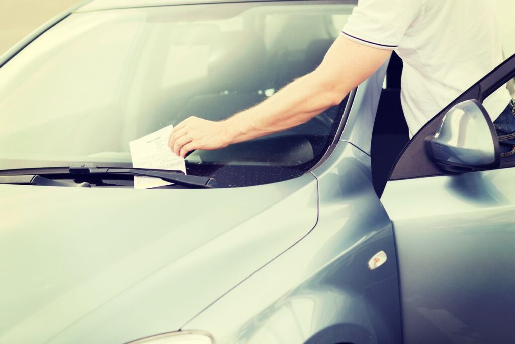 Uomo toglie una multa dal parabrezza della sua auto